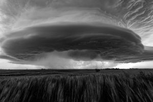 A cyclone-shaped storm cell grows over a field of wheat and grass