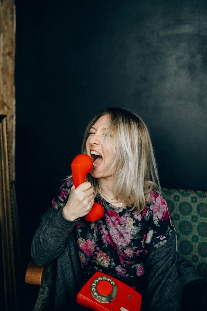 A woman screams angrily into a phone. | Phoot Credit: Nataliya Vaitkevich