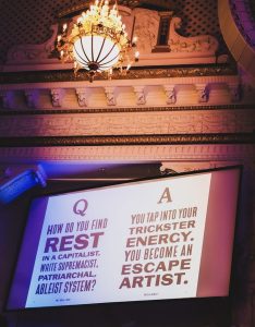 At an event held by the Nap Ministry, a slide asks the question: "How do you find rest in a capitalist, white supremacist, patriarchal, ableist system?" The answer reads: "You tap into your trickster energy. You become an escape artist." Photo Credit: Tricia Hersey