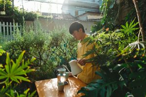 A young man prepares pour over coffee in his verdant, vibrant backyard in the city. Photo Credit: Khoa Vo